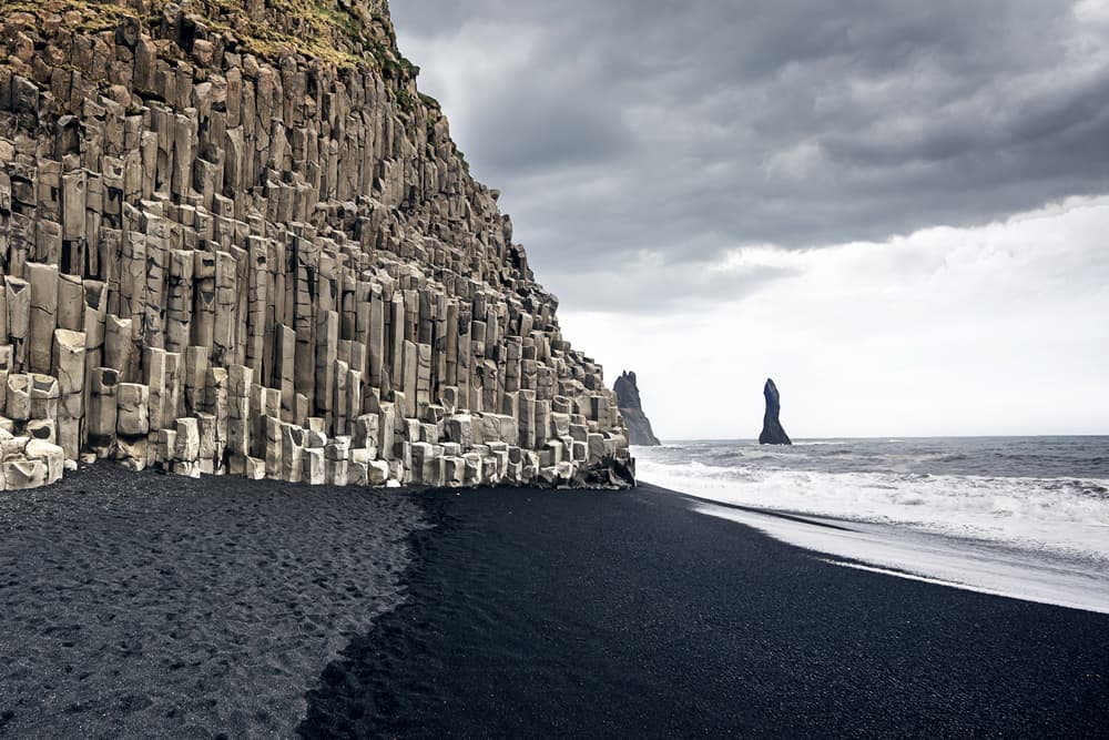 Basalt columns at Reynisfjara Black Sand Beach under a cloudy sky.