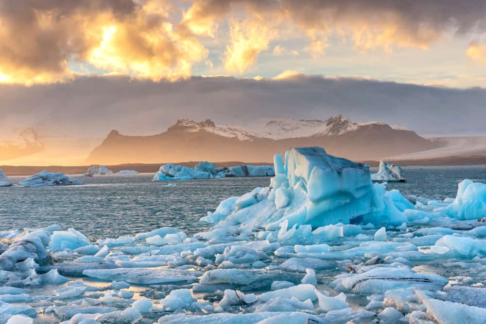 Floating icebergs at Jokulsarlon Glacier Lagoon with golden clouds overhead.