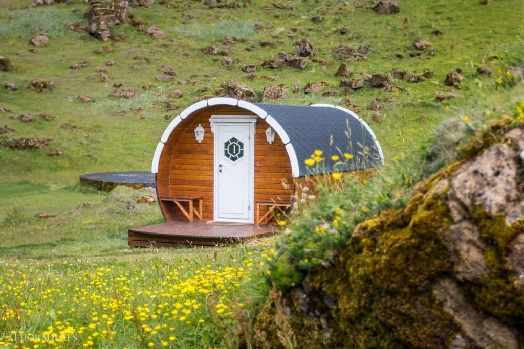 small circular wooden structure with a white door in a field