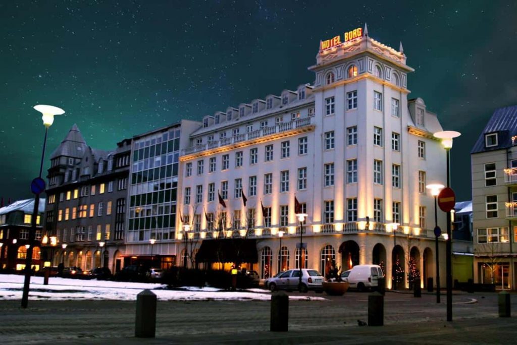 a hotel in reykjavik iceland at night with northern lights and stars in the sky