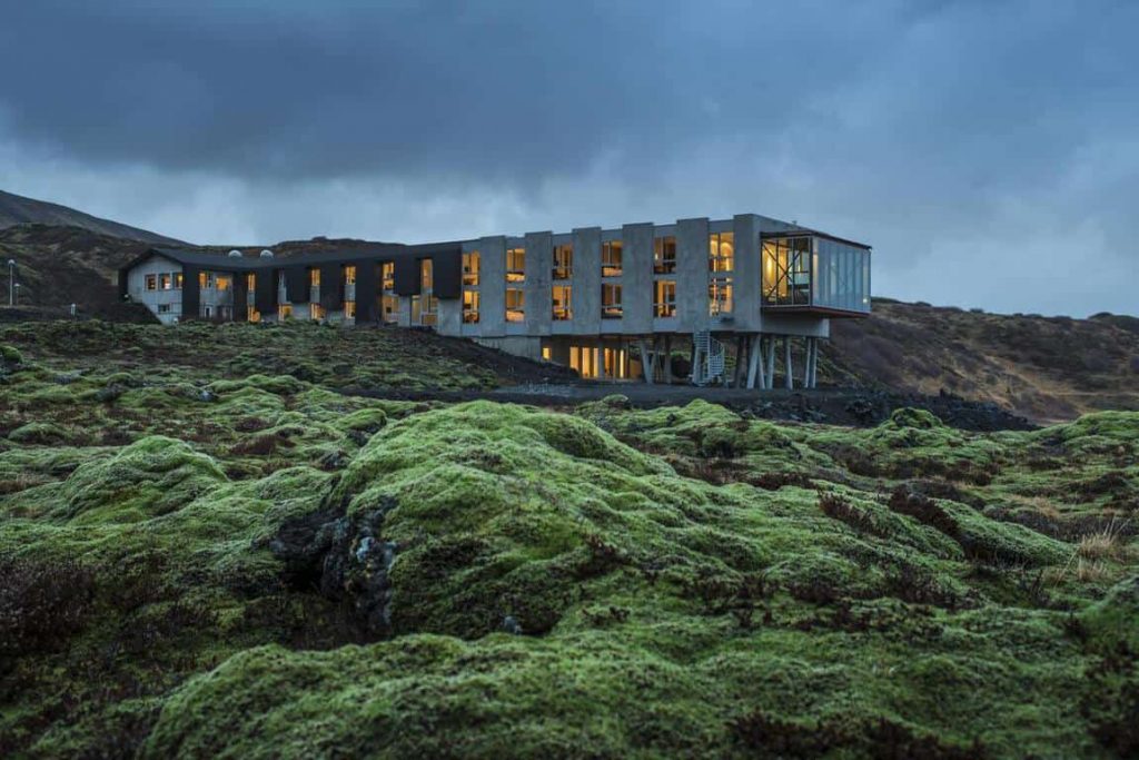 Ion Adventure Hotel in iceland at night with lights on and lava rocks covered by moss 