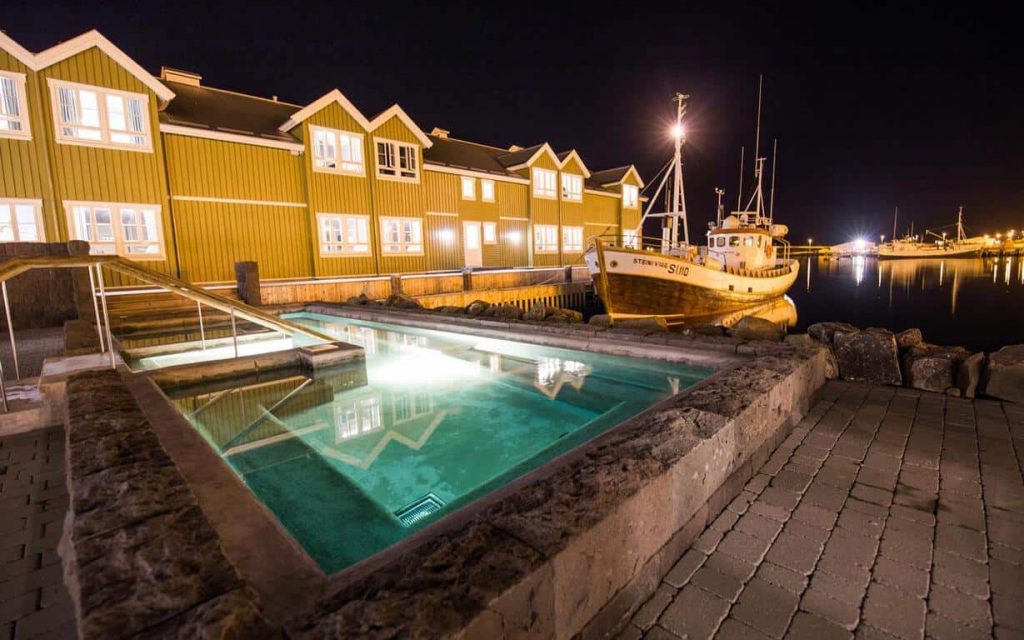 Siglo Hotel at night with a pool in the foreground a docked boat at the base of the hotel