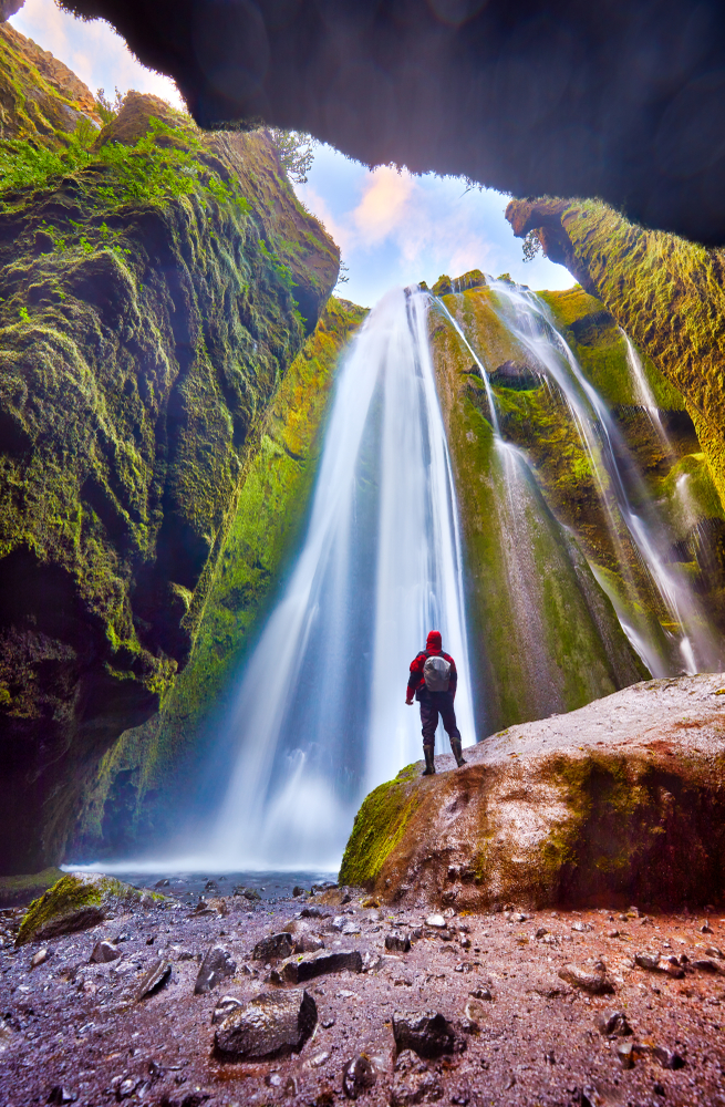Person in red standing in front of Gljufrabui hidden waterfall 