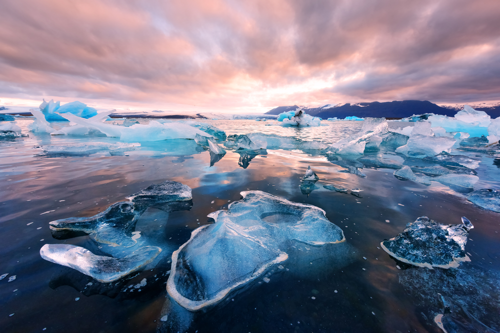 diamond beach in iceland at sunset with blue icebergs in foreground