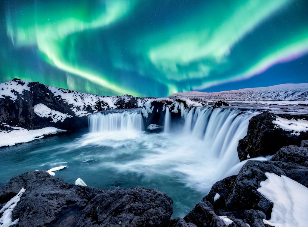 snow covered semi circle waterfall with Northern Lights