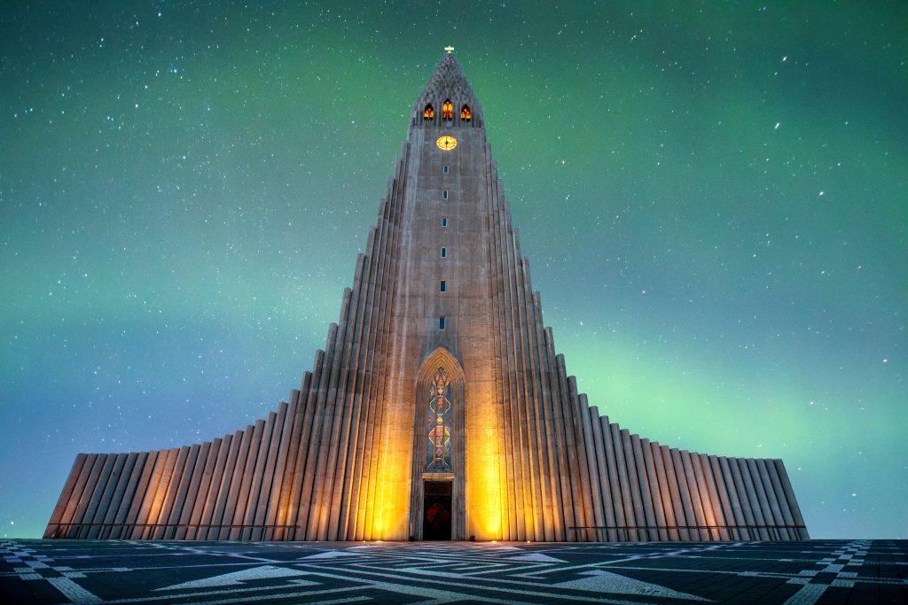 towering church framed by Northern Lights best things to do in Iceland