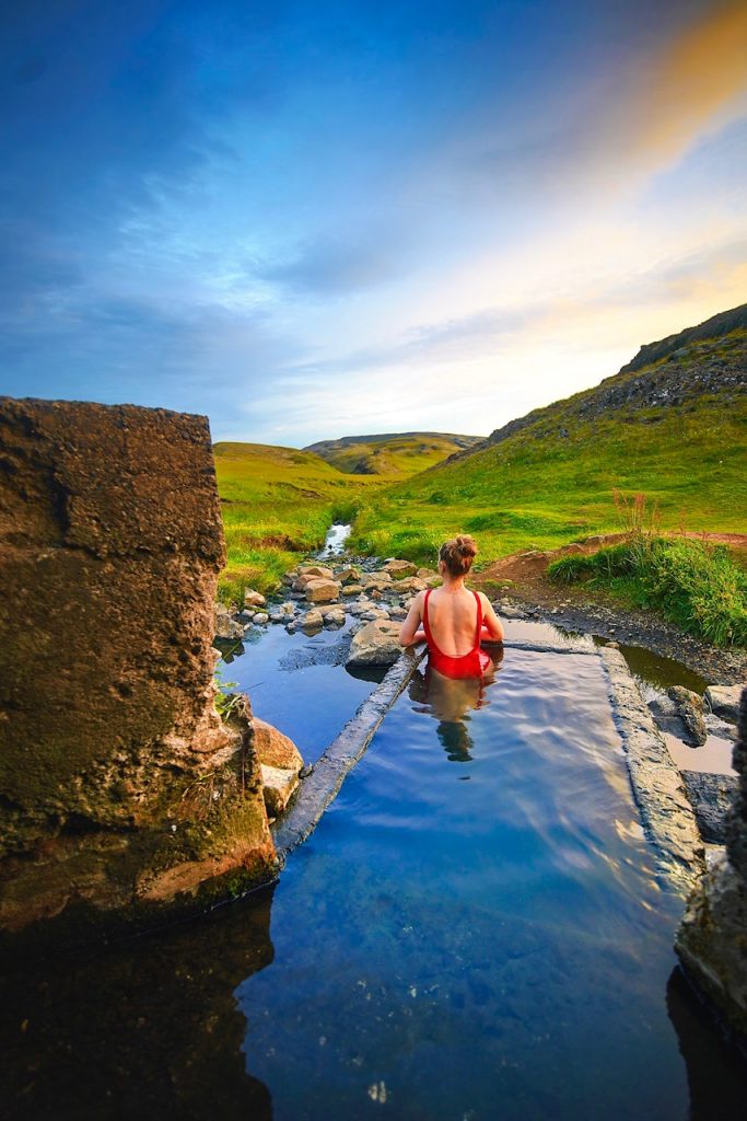 woman sitting in Hrunalaug hot springs best things to do in Iceland