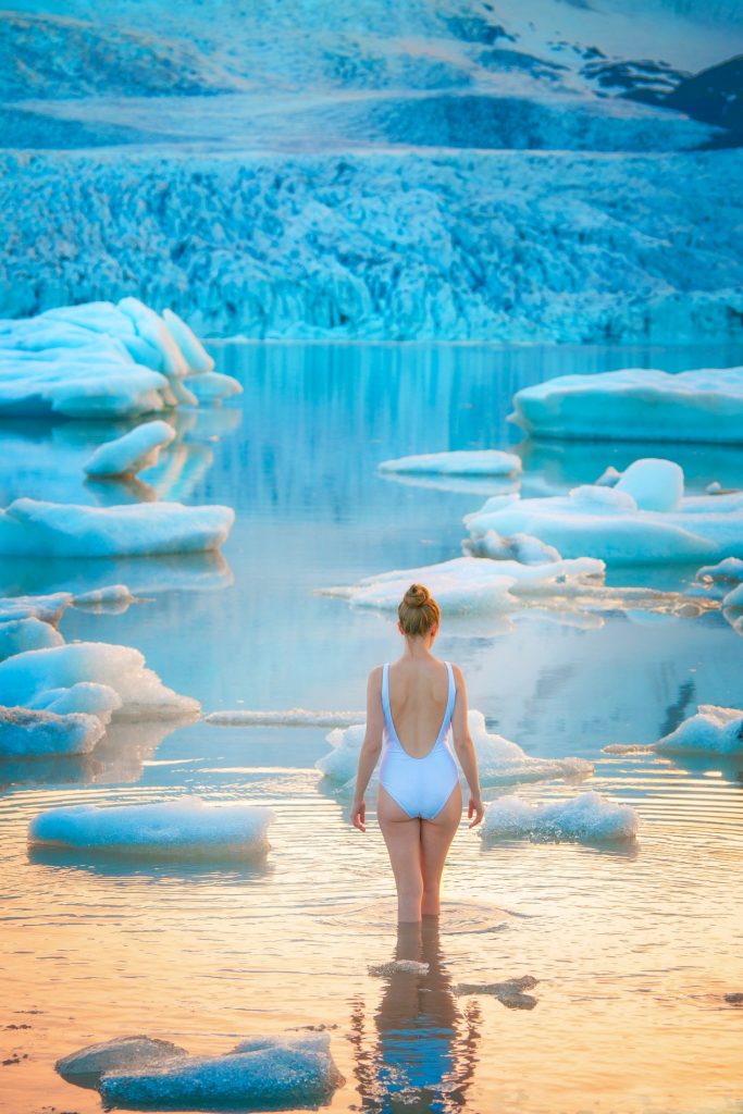 woman wading in Jokulsarlon glacier lagoon with a swim suit.