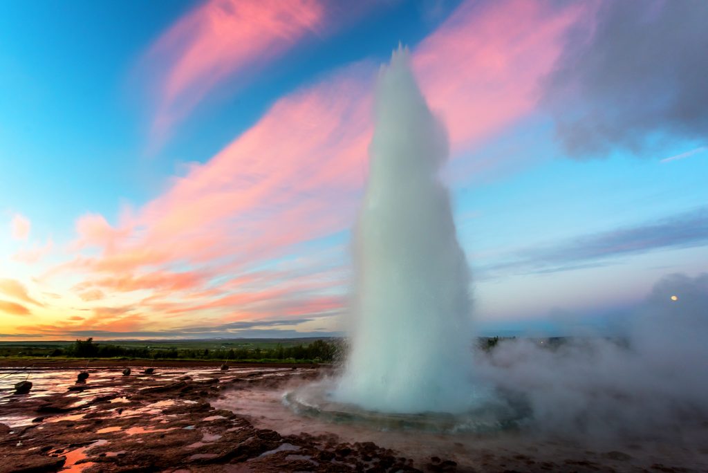 geyser shooting into the air at sunset best things to do in Iceland
