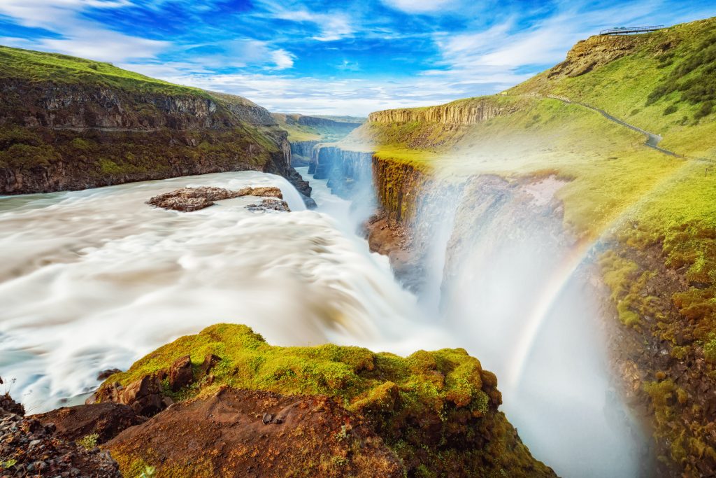 rainbow over gullfoss waterfall on a sunny day with blue sky