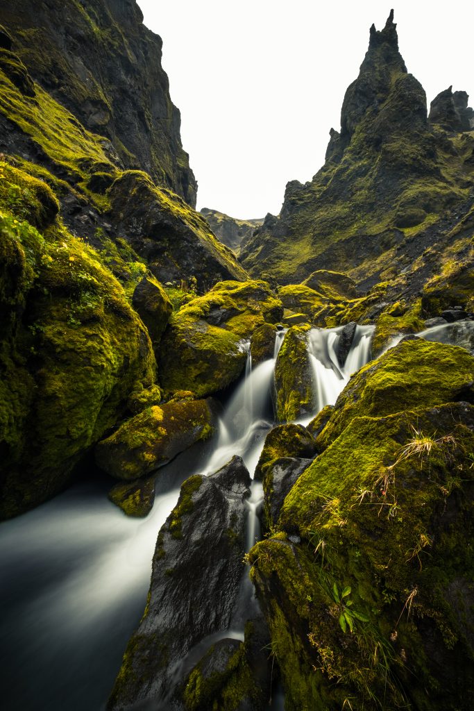 Sharp mountain peaks covered in greenery with adjacent waterfall