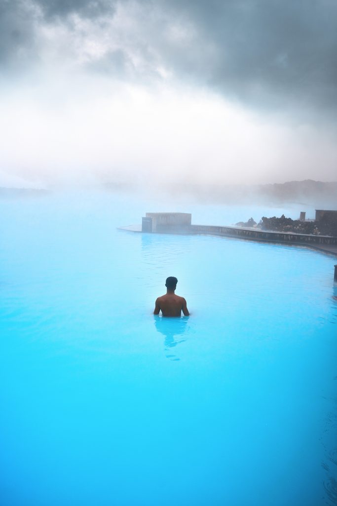 A man standing in the foggy Blue Lagoon in Iceland.