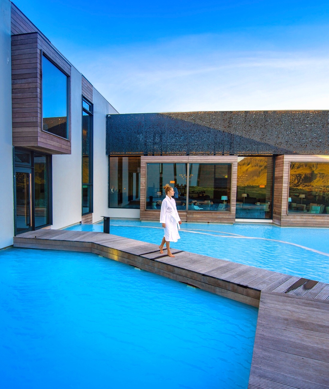 Woman walking in robe across blue waters at the Blue Lagoon Retreat hotel