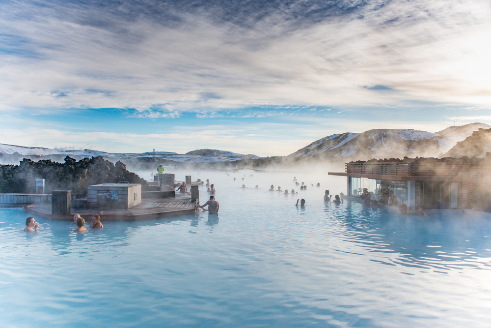 Blue Lagoon Iceland with people bathing and mountains in background.