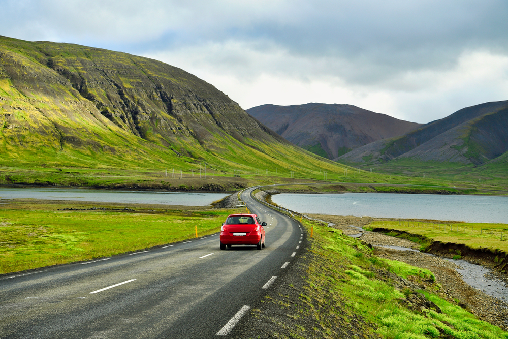 Car driving down road in Iceland showing how to get around while camping in Iceland.