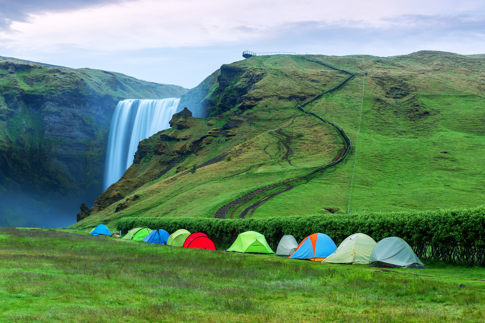 A line of tents for camping in Iceland near the Skogafoss Waterfall.