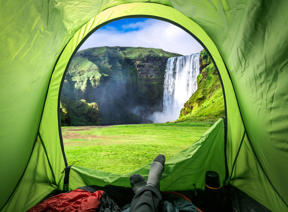 Camping in Iceland with a view of Skogafoss Waterfall out of a tent.