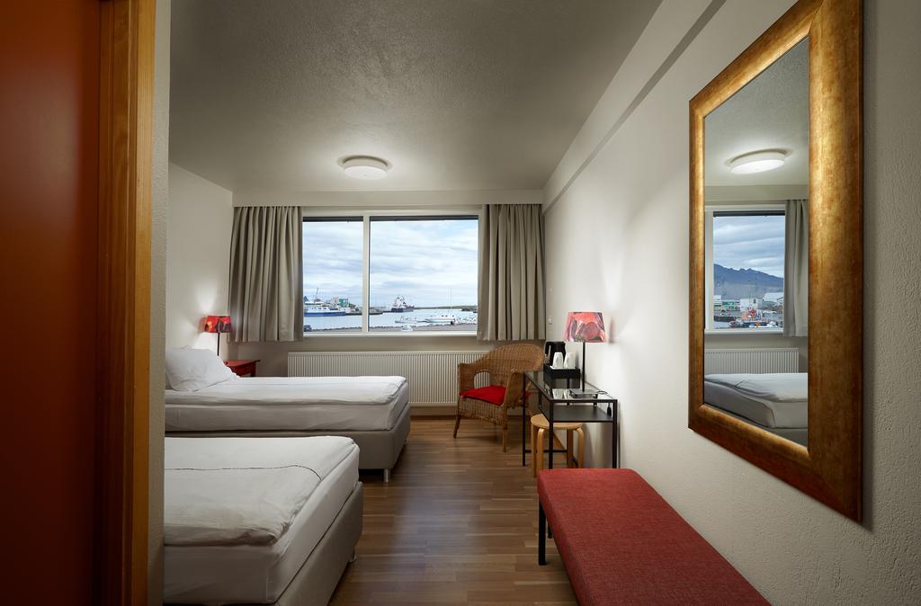 Photo of guest room at Hotel Edda Hofn which is located in Iceland. View of the harbor is seen with boats. 