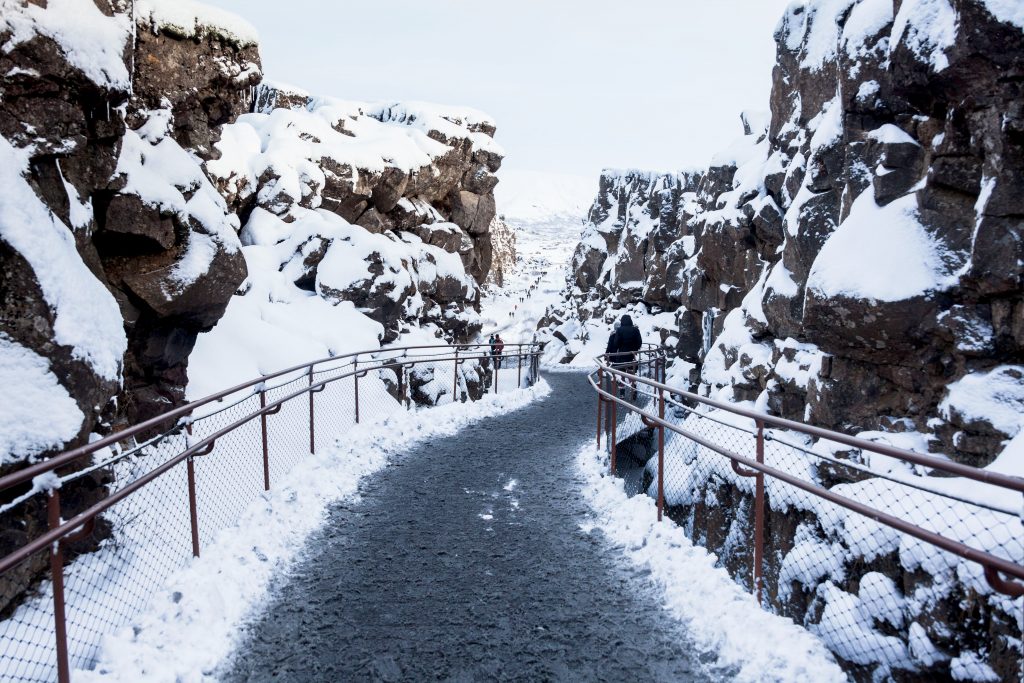 pathway surrounded by lava rocks covered in snow
