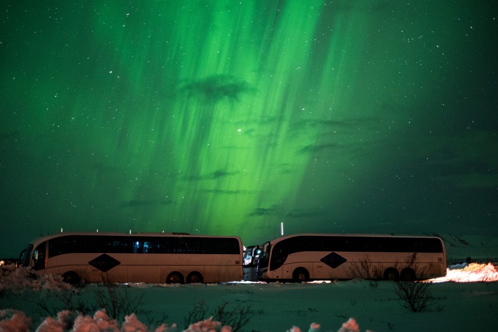 two buses in front of aurora borealis