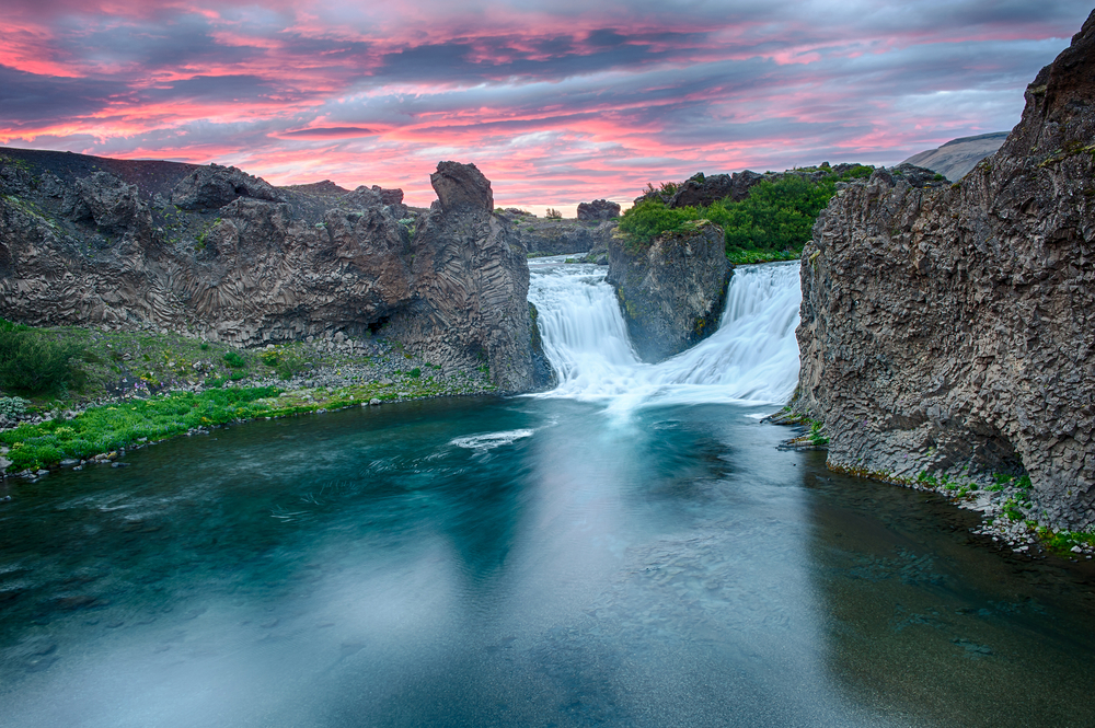 a double waterfall flowing into a calm water at sunset