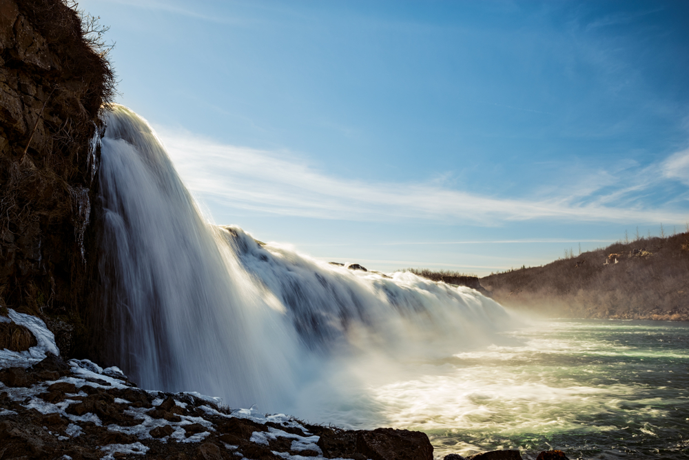 side angle of a short waterfall lowing into the river below