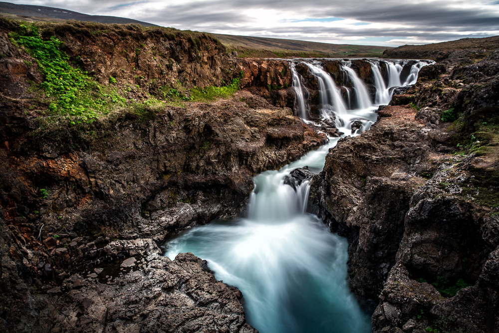 Kolugljufur falls is impressive with water thundering down the gorge on a cloudy day