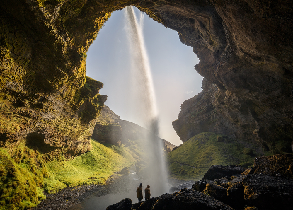 two people walking behind Kvernufoss Waterfall
