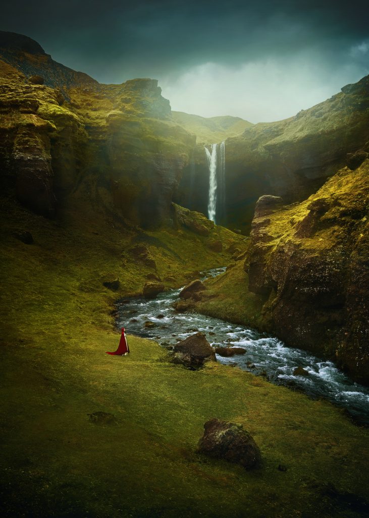 fine art photography of mystical photo of a woman standing in a cape at Kvernufoss Waterfall