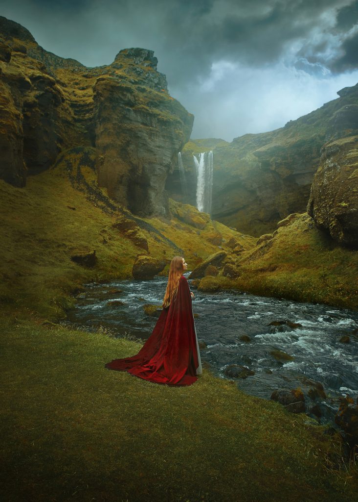 close up image of a woman wearing a cape at Kvernufoss Waterfall in Iceland