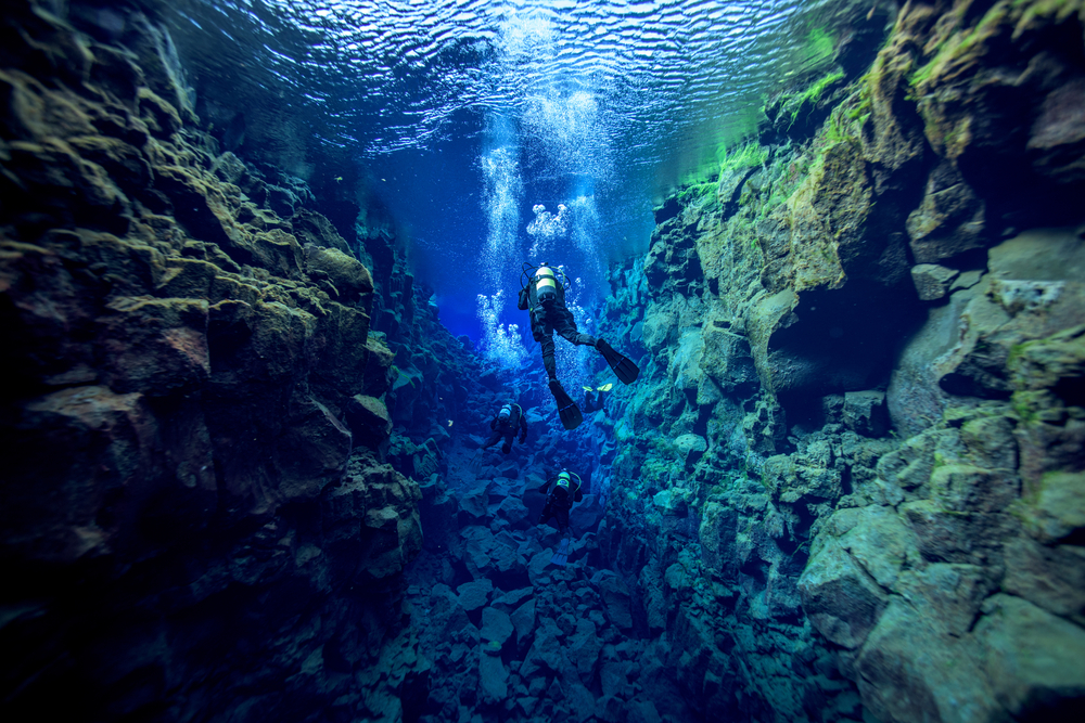 3 people snorkeling between two tectonic plates in iceland