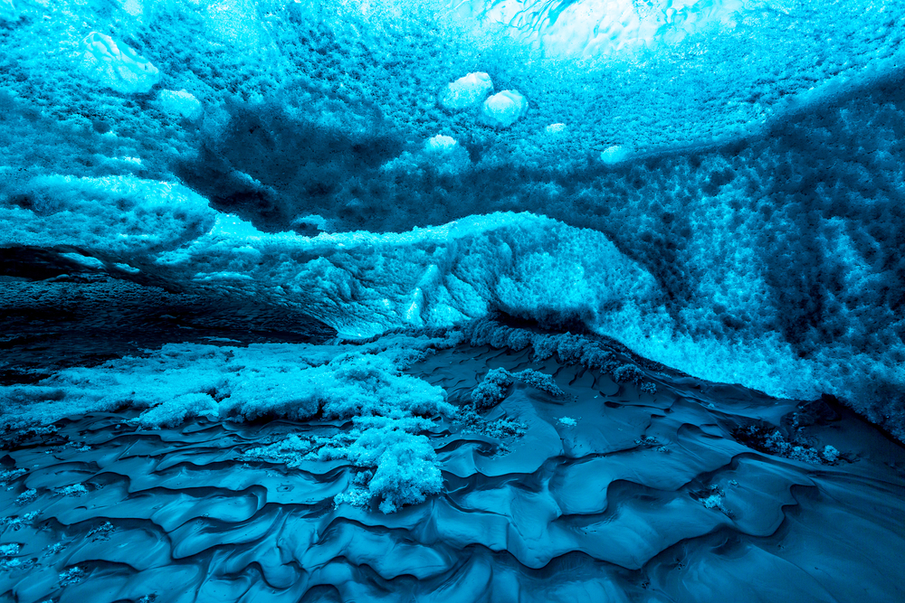 blue ice from underwater with layers of sand beneath