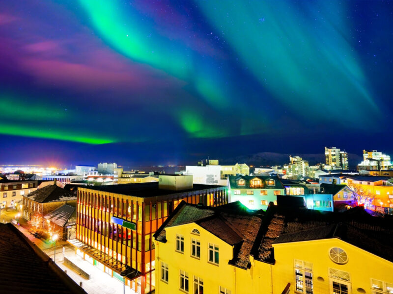 The streets of Reykjavik lit by purple, green, and blue Northern Lights.