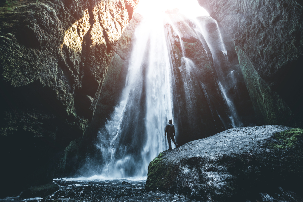 Photo of a man before a waterfall.