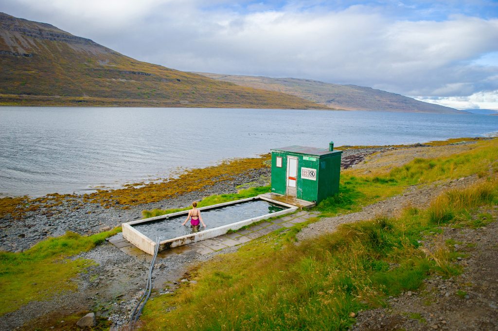 Girl in a hot spring pool next to a lake.