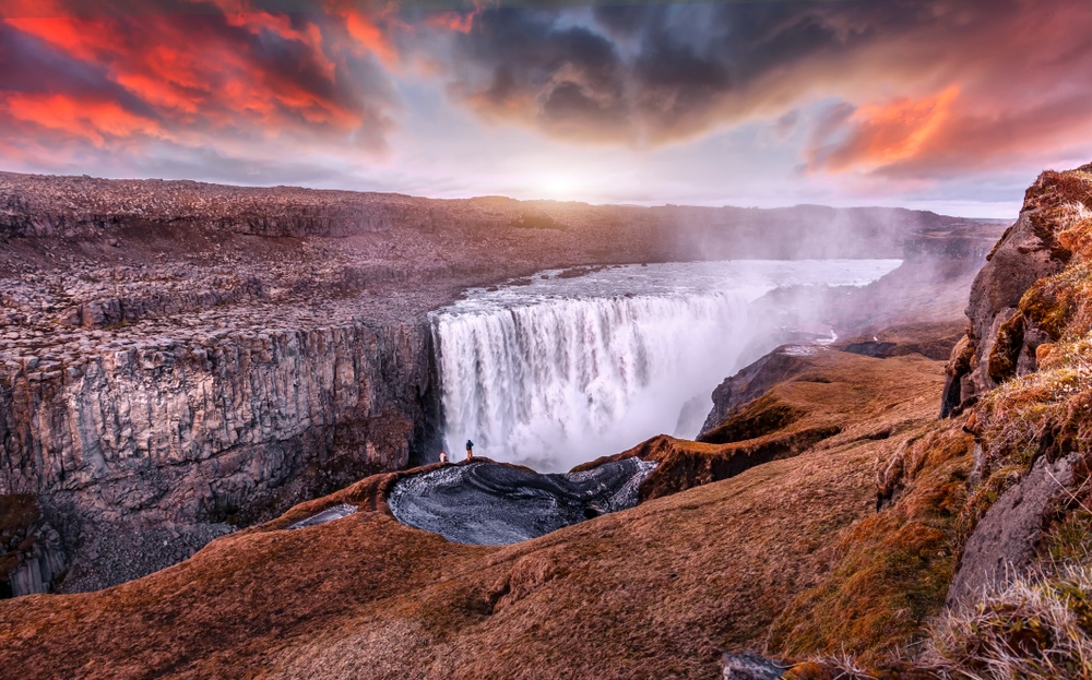 photo of the iconic Dettifoss waterfall, one of the most powerful waterfalls in the world. There is a dramatic sunset sky in the background