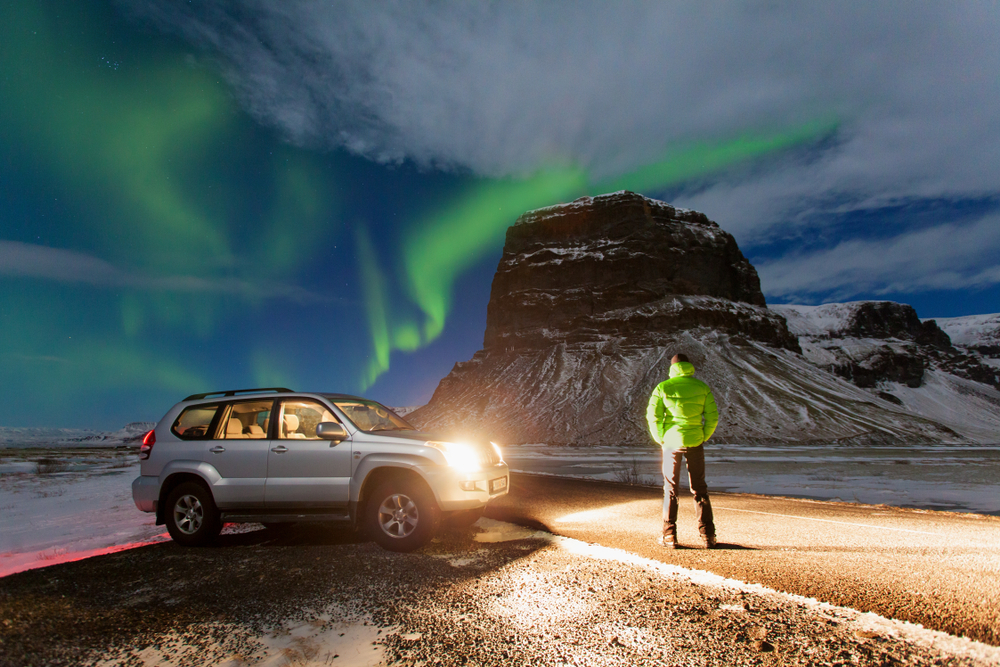 Photo of a car and Northern Lights in Iceland.