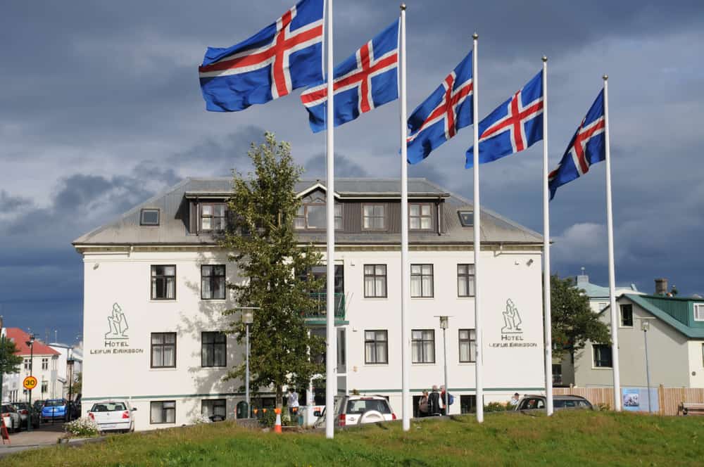 a white hotel with 5 icelandic flags flying in front of it.
