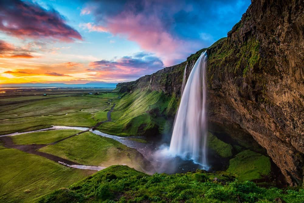 Seljalandsfoss waterfall surrounded by lush green landscape at sunset