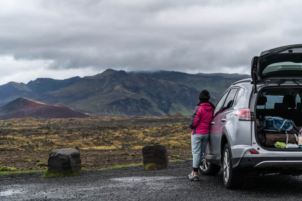 person leaning on a car in iceland before a hike