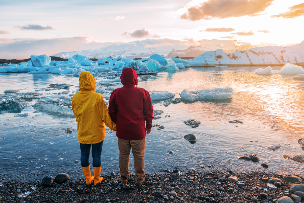 Photo of couple standing in front of a glacier in Iceland.