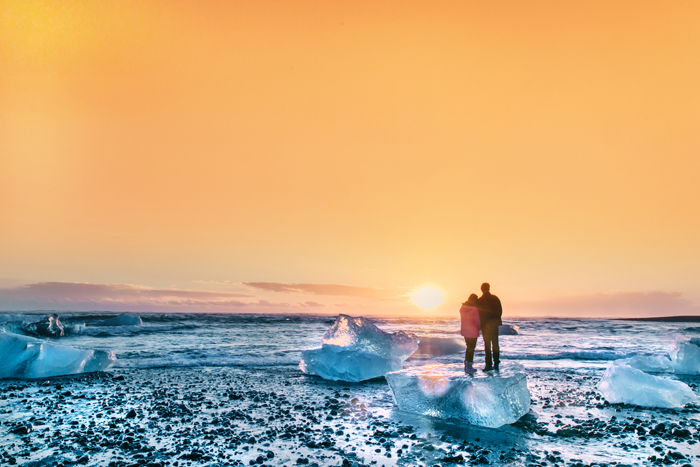 Photo of couple standing on ice melts in Iceland.