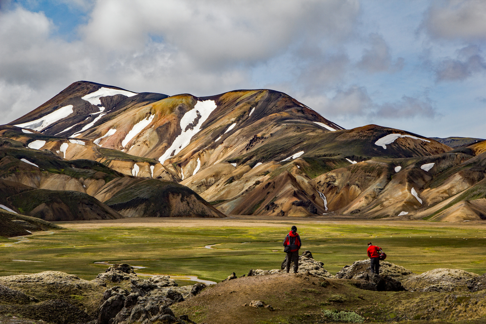 photo of two hikers on the Laugavegur trail which you can hike when you visit iceland national parks. There are mountains in the background.