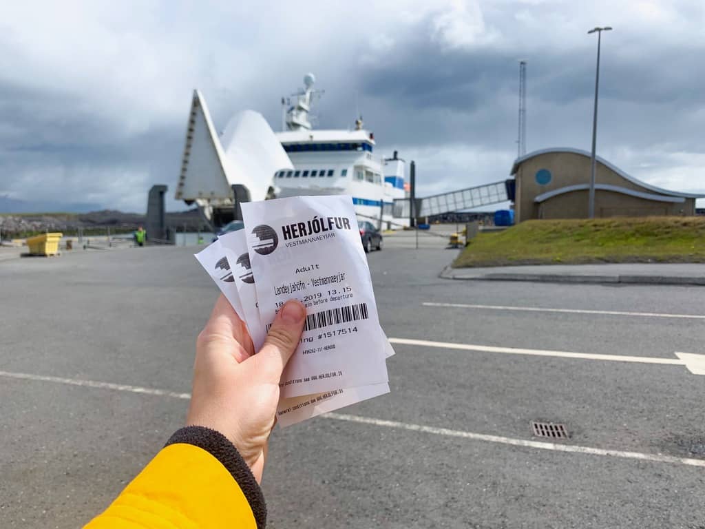 holding tickets to the westman islands ferry on the mainland