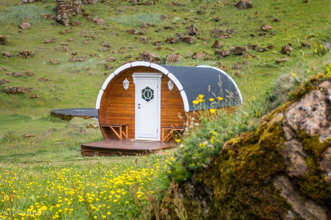 a cabin shaped like a barrel with a white door in an icelandic landscape 