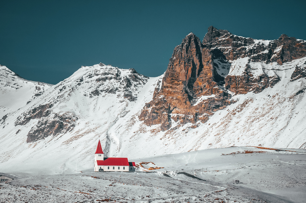 a church in Iceland with snowy mountains in the background 