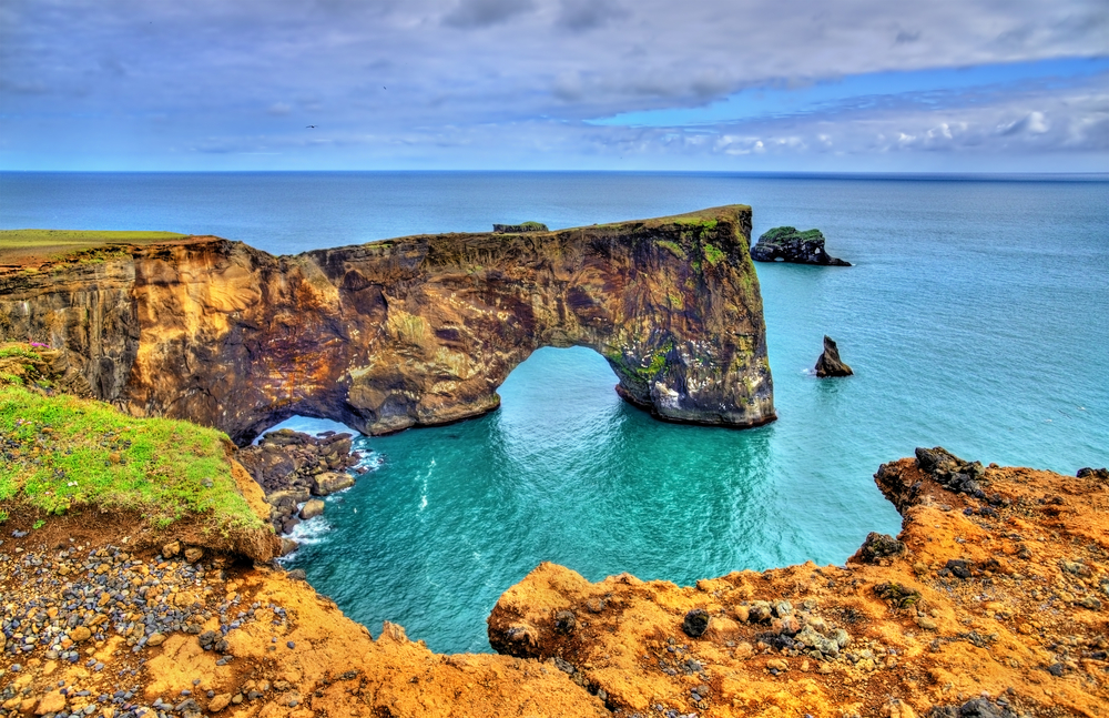 Looking down at the Dyrholaey arch in the blue ocean.