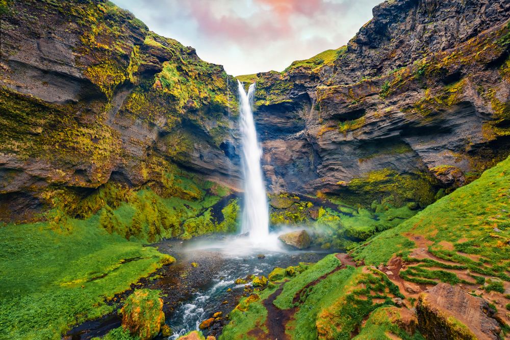 Kvernufoss Waterfall falling into a mossy gorge.