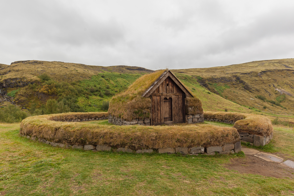 A building with a turf-roof and circle fence at the Reconstructed Farm.