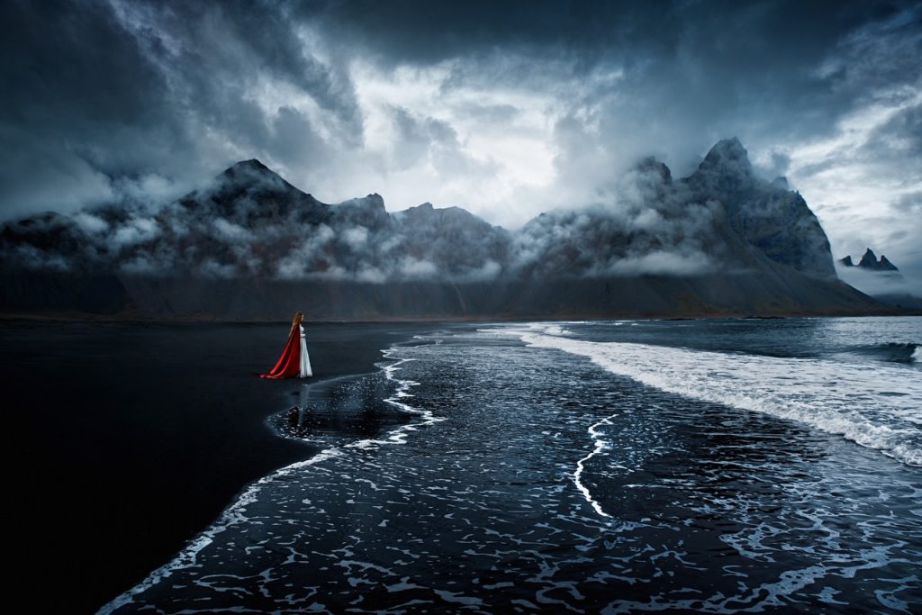 woman standing alone on black sand beach Iceland wedding